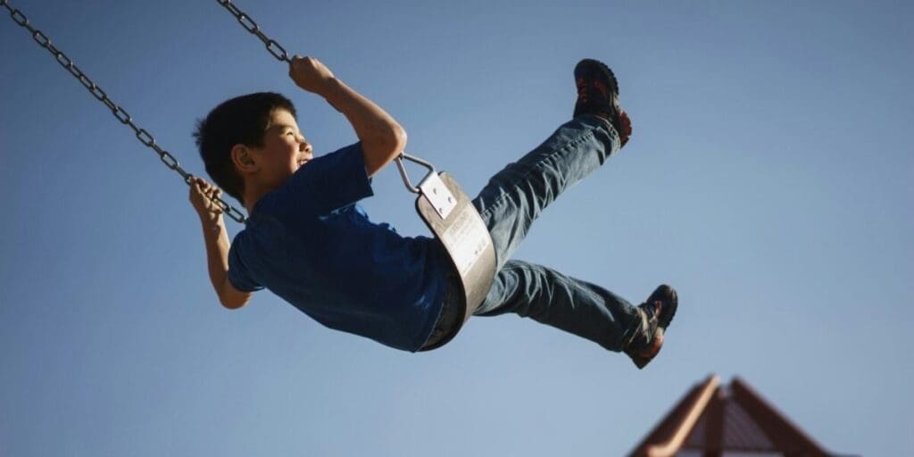 Young Boy Swinging on a Playground